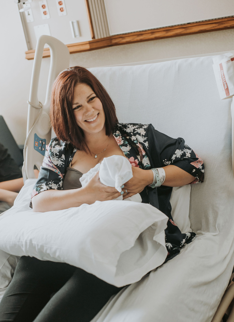 Newborn Photographer, a mother breast feeds her baby in the hospital bed