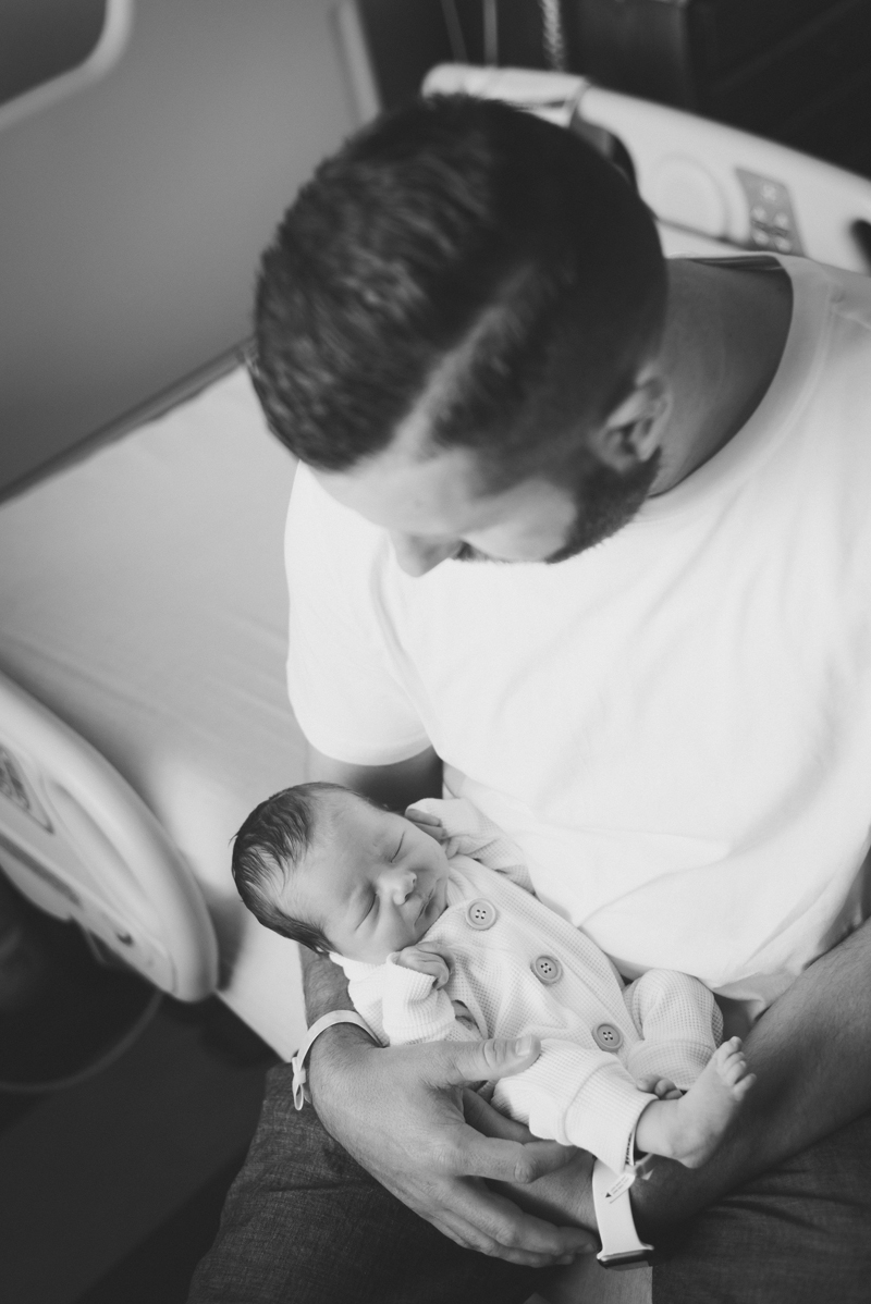 Newborn Photographer, a father holds his little baby in the hospital