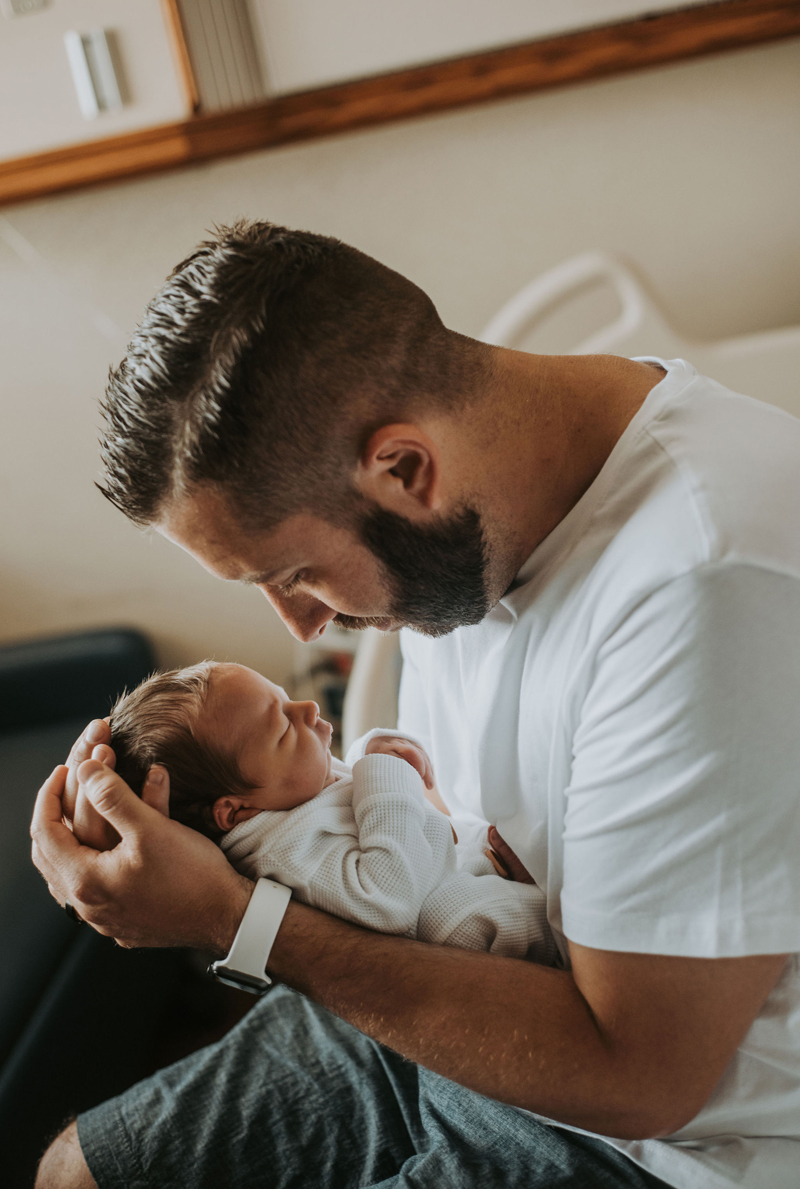 Newborn Photographer, A Father holds his baby son in his arms and gazes at him