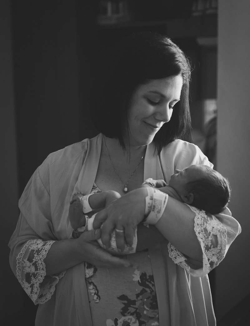 Newborn Photographer, a mother smiles in admiration as she holds her new baby
