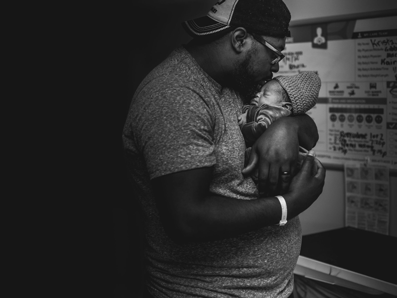 Newborn Photographer, a father kisses his newborn baby son on the forehead