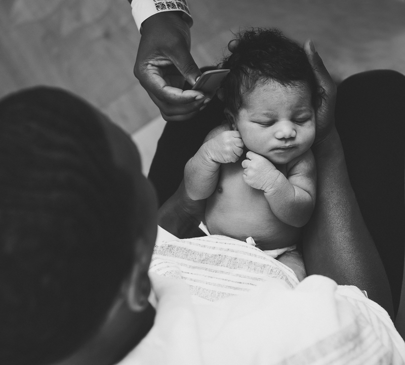 Newborn Photographer, A Father holds his baby boy as mom's hand reaches in with small comb to comb his full head of hair