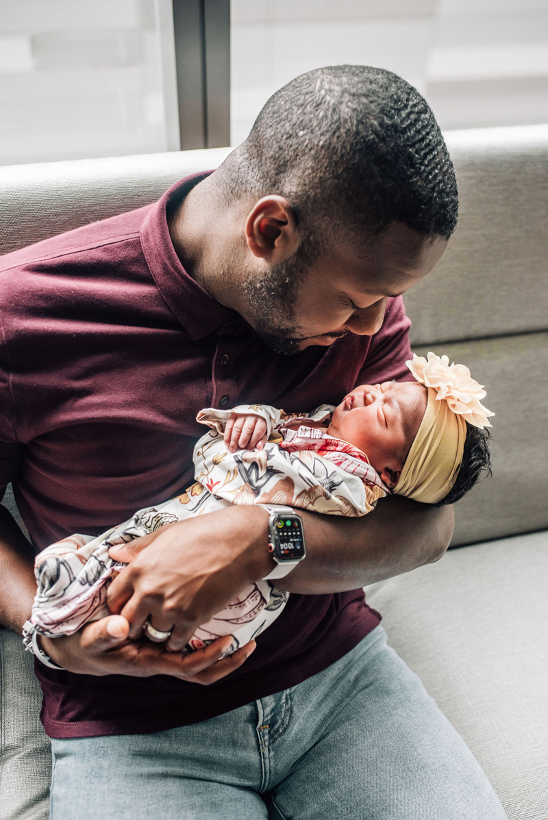 Newborn Photographer, a father gazes at his baby girl as he holds her in his arms