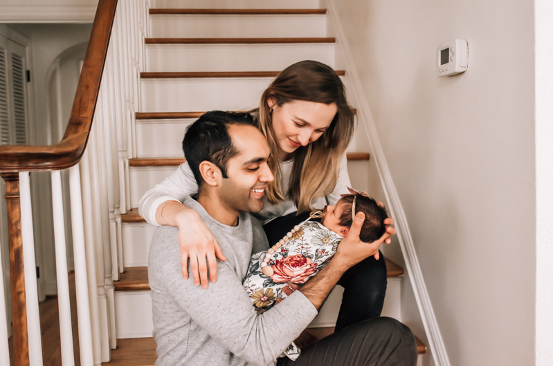 Newborn Photographer, a young mother and father admire their baby at the foot of the stairs